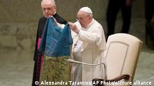 Pope Francis shows a flag that he said was brought to him from Bucha, Ukraine, during his weekly general audience in the Paul VI Hall, at the Vatican, Wednesday, April 6, 2022. (AP Photo/Alessandra Tarantino)
