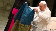 Pope Francis holds a flag of Ukraine that comes from the city of Bucha, one of the areas around Ukraine's capital from which Russian troops have withdrawn and where dozens of bodies in civilian clothing have been found, during the weekly general audience on April 6, 2022 at Paul-VI hall in The Vatican. (Photo by Andreas SOLARO / AFP)