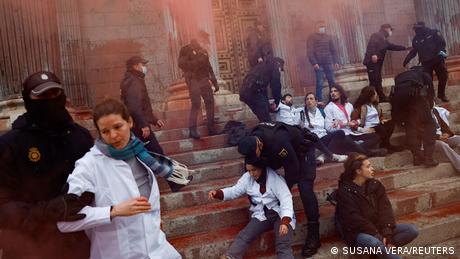 Police officers try to stop activists from throwing red paint at the Spanish parliament
