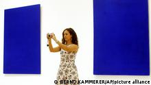 Una mujer se toma una foto entre dos lienzos de azul ultramarino.