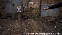 06.04.2022 Ein Zeuge gestikuliert neben dem Grab von zwei Zivilisten, die in einem Hinterhof in Butscha begraben wurden. +++ dpa-Bildfunk +++