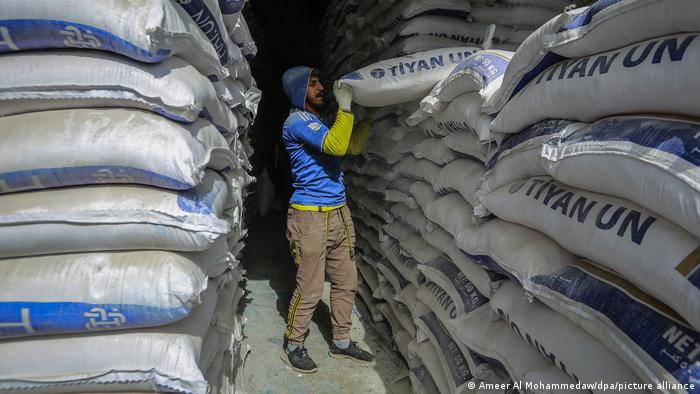 Un trabajador apila sacos de harina en el almacén de un mercado.