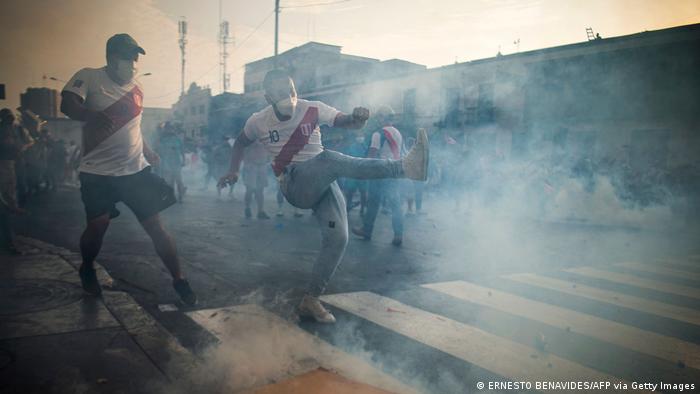 Pengunjuk rasa yang menggunakan masker di jalannan di Lima, dengan gas air mata di udara. (Foto oleh ERNESTO BENAVIDES/AFP via Getty Images)