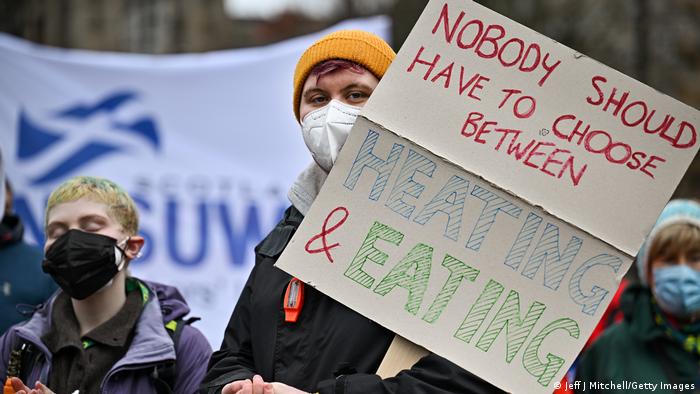 Seorang pengunjuk rasa di Glasgow memegang plakat bertuliskan Tidak seorang pun harus memilih antara pemanasan & makan. (Jeff J Mitchell/Getty Images)
