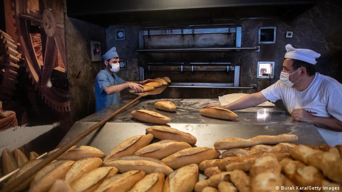 Two masked bakers in a bakery in Istanbul, loaves of bread in the foreground. (Photo by Burak Kara/Getty Images)