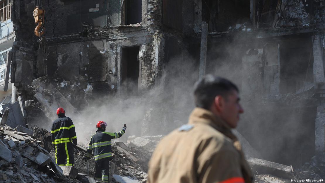 Homens dos servi&ccedil;os de resgate observam pr&eacute;dio destru&iacute;do