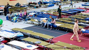 Refugees from Ukraine sit on cots in a large accommodation facility in Germany