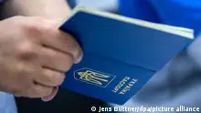 A hand holds a Ukranian passport