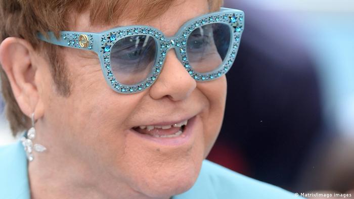 Elton John wearing starry blue sunglasses.