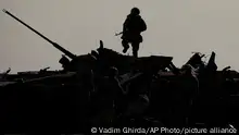 A Ukrainian serviceman walks on a destroyed Russian fighting vehicle in Bucha, Ukraine, Thursday, April 7, 2022. (AP Photo/Vadim Ghirda)