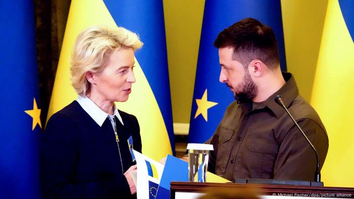 EU Commission President Ursula von der Leyen (l) and Ukrainian President Volodymyr Zelenskyy speaking at a press conference with Ukrainian and EU flags in the background