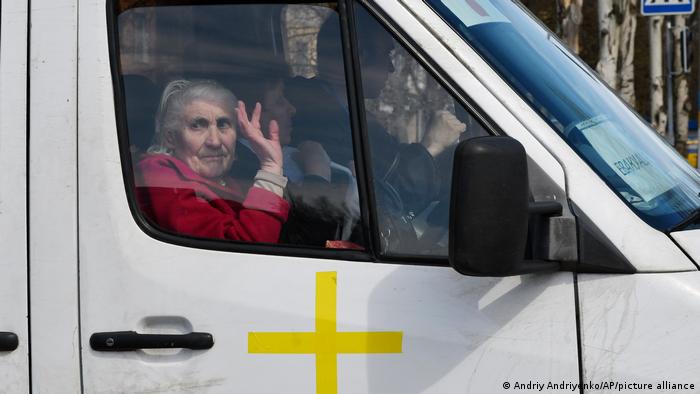 Пожилая женщина на пассажирском сиденье микроавтобуса с желтым крестом в Краматорске