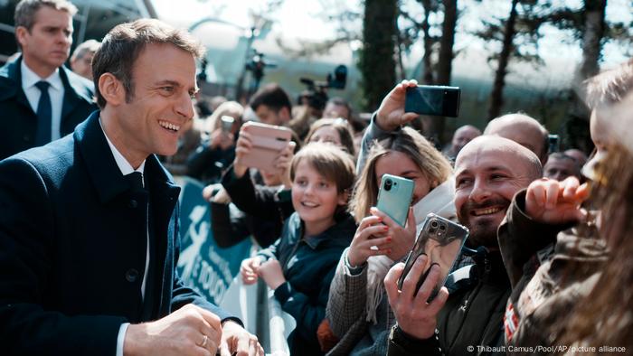 President Emmanuel Macron smiles to residents after voting for the first round of the presidential election in Le Touquet, France