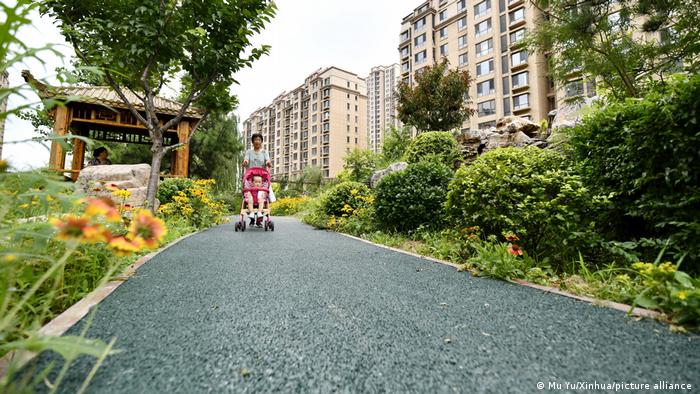 A woman walks with her child on a trail paved with permeable surface at a residential compound in Qian'an City of north China's Hebei Province