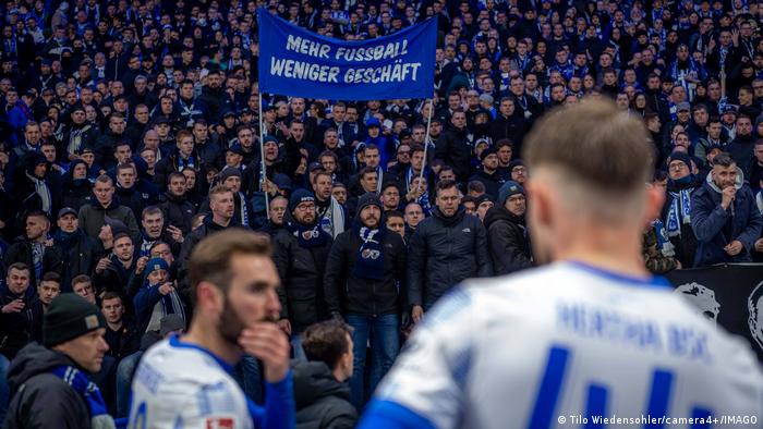 Los ultras enojados del Hertha Berlín se enfrentan a los jugadores después de la derrota en el derbi ante Union.  Una pancarta dice: Más fútbol, ​​menos negocios 