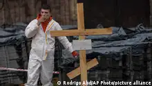 10.04.2022 *** Ein Friedhofsarbeiter macht eine Pause von der Arbeit an einem Massengrab bei der Identifizierung von Zivilisten, die während des Krieges getötet wurden. +++ dpa-Bildfunk +++