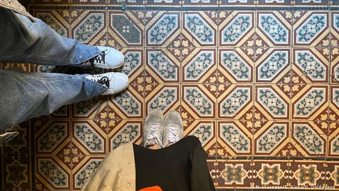 Двоє людей на викладеній мозаїкою підлозі у Львові, Україна 