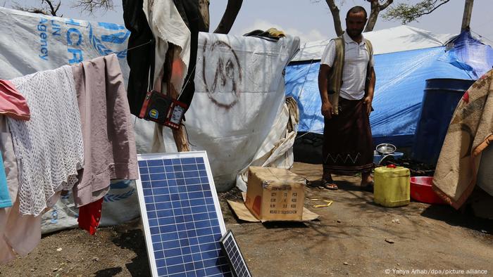A displaced man stands near solar panels outside makeshift shelters at a camp for Internally Displaced Persons (IDPs) in the northern province of Amran, Yemen.