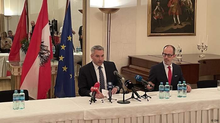 Austrian Chancellor Karl Nehammer at a press conference in Moscow in front of Austrian and EU flags; beside him is another official