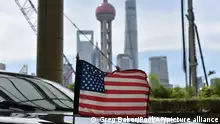 A U.S. flag flies on a U.S. consulate car, with the backdrop of buildings in the Lujiazui financial district, outside a hotel where U.S. trade negotiators are staying, in Shanghai Wednesday, July 31, 2019. (Greg Baker/Pool Photo via AP)