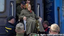 Ukrainian servicemen help an elderly woman to board a train as she flees Russia's invasion of Ukraine at a railway station in Sloviansk, Ukraine, April 11, 2022. REUTERS/Marko Djurica
