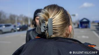Женщина стоит спиной к объективу и рассказывает об изнасилованиях в Запорожье