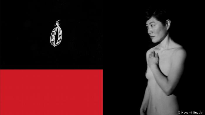 A naked woman stands against a black background with her hand across her chest while looking at a pod of peas suspended in the air above a red rectangle