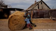 Ivan Bonderenko and his grandsons Marat and Renat push a bale of hay in the village of Yakovlivka, outside Kharkiv, after it was attacked in an aerial bombardment as Russia's attack on Ukraine continues, April 2, 2022. REUTERS/Thomas Peter SEARCH YAKOVLIVKA FOR THIS STORY. SEARCH WIDER IMAGE FOR ALL STORIES