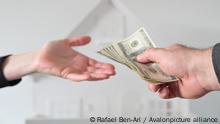 Two people (male and female) passing money against a white house. Mortgage, housing market, home loans and property, management concept. No people. Copy space, Credit:Rafael Ben-Ari / Avalon
