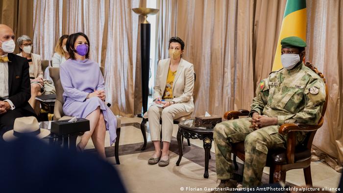 Außenministerin Annalena Baerbock sitzt am Rand eines mit Vorhängen verhängten Raums; auf einem Sessel mit Armlehnen in der Mitte sitzt der Anführer der Militärjunta Malis, Assimi Goita. Beide tragen Mundschutz.