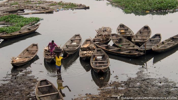 Workers carry wood chunks from boats near okobaba sawmill, Lagos, Nigeria