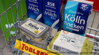 A grocery cart is filled with essential food items at a store in Germany
