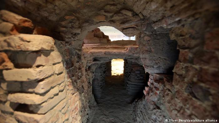 A cross-section photo shows a brick tunnel extending under the floor of a Roman building .