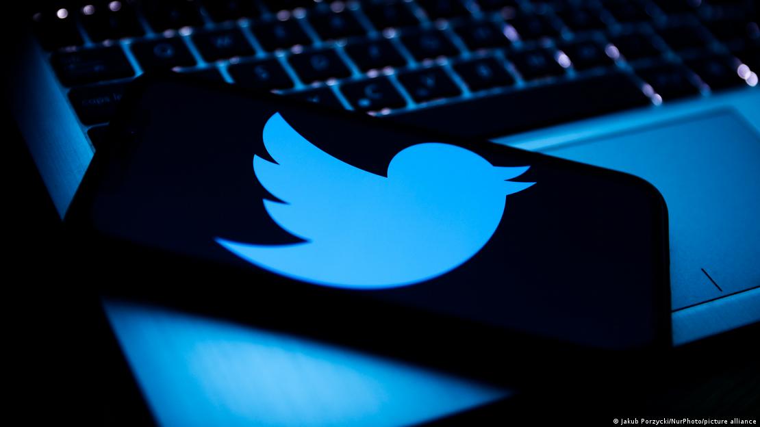 Logo do Twitter em celular em cima de um teclado de notebook