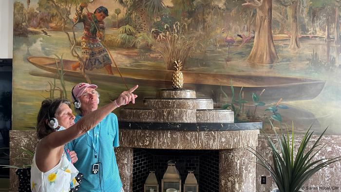 A tourist points while in front of a fireplace of a lobby in the Essex House Hotel.