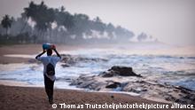 Ein Mann den Strand von Elmina in Ghana entlang