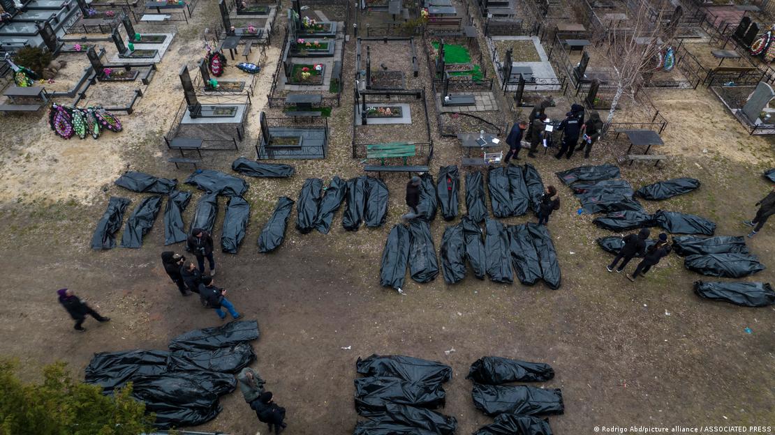 Muitos corpos dentro de sacos pretos em um cemitério