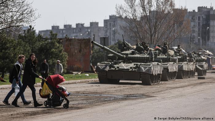 Civiles con un niño caminan en la cercanía de tanques rusos en Mariúpol, Ucrania.