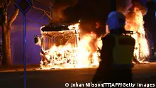 TOPSHOT - An anti-riot police officer stands next to a city bus burning in Malmo late April 16, 2022. - The unrest in Malmo has continued after Rasmus Paludan, party leader of the Danish right-wing extremist party Tight Course, held a demonstration on April 16, 2022 at Skanegarden near the Oresund Bridge. - Sweden OUT (Photo by Johan NILSSON / TT NEWS AGENCY / AFP) / Sweden OUT (Photo by JOHAN NILSSON/TT NEWS AGENCY/AFP via Getty Images)
