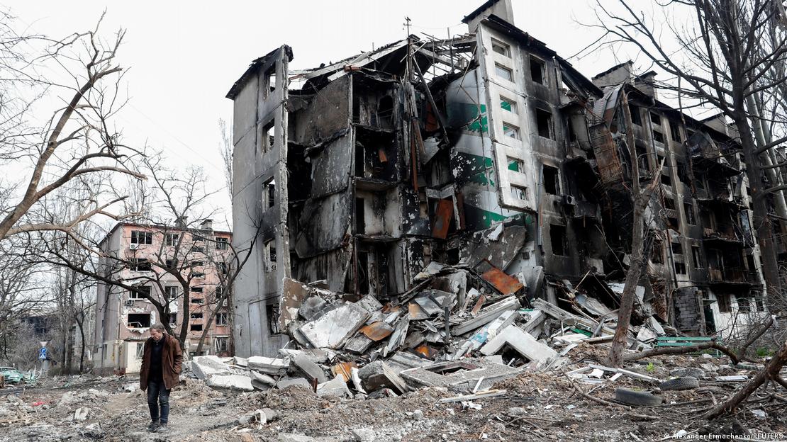 Homem caminha entre escombros de prédio residencial em Mariupol