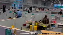 In this image taken from video provided by Beibei, who asked to be identified only by her given name, residents take a rest at the National Exhibition and Convention Center which converted to a quarantine facility set up for people who tested positive but have few or no symptoms on April 15, 2022, in Shanghai. (Beibei via AP)