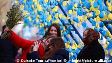 A blue and yellow Ukrainian flag-colored object is set in Lviv City, western Ukraine, on April 17, 2022. Many families take commemorative photos and pass by while smiling.( The Yomiuri Shimbun via AP Images )