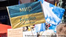«Frieden für die Ukraine» steht während der Abschlusskundgebung der Ostermärsche des «Netzwerks Friedenskooperative» in Frankfurt und Umgebung auf einem Schild. Im Hintergrund ist eine Fahne mit Friedenstaube zu sehen. Unter dem Motto «Die Waffen nieder! Stoppt den Krieg in der Ukraine. Stoppt das 100-Milliarden-Euro-Aufrüstungsprogramm» nahmen mehrere hundert Teilnehmer an dem Ostermarsch teil. +++ dpa-Bildfunk +++