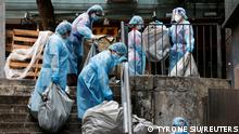 Cleaners in personal protective equipment dump garbage outside a quarantine hotel in Hong Kong
