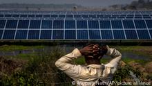 52-year old farmer Sitaram Murmu, whose agriculture land had been transfered to build a solar power plant stands near the plant in Mikir Bamuni village, Nagaon district, northeastern Assam state, India, Feb. 18, 2022. Protests have been simmering among several poor families belonging to India's indigenous communities who contest the sale of 91 acres of land to New Delhi-based green energy producer Azure Power Global Limited. The dispute underscores not just India’s often fuzzy land ownership rules complicated by colonial-era land classifications, but also the immensity of the challenges facing India in its renewable goals for the next decade. (AP Photo/Anupam Nath)