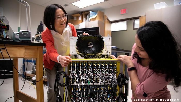 Zhen Xu, catedrática de Ingeniería Biomédica de la Universidad de Michigan (izquierda) y Tejaswi Worlikar, estudiante de doctorado de Ingeniería Biomédica, hablan del transductor de ultrasonidos de 700 kHz y 260 elementos que utilizan en el laboratorio de la profesora Xu. 