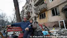 Pensioners Vladimir Yakovlev ,69, and his wife Lyudmila, 67, sit on a bench in a courtyard near a block of flats heavily damaged during Ukraine-Russia conflict in the southern port city of Mariupol, Ukraine April 18, 2022. REUTERS/Alexander Ermochenko