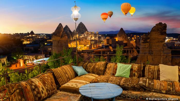A view from a roof terrace at daybreak, as hot air balloons float by