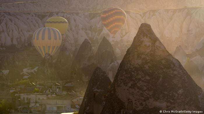 Tourists ride hot air balloons near the town of Goreme, in the early morning light