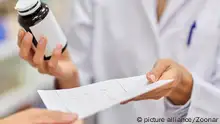 medicine, pharmaceutics, healthcare and people concept - pharmacist with drug taking prescription from customer at drugstore